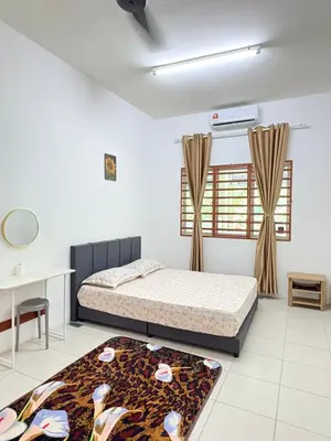 a bedroom with a bed and a table and a rug at Home-Away Homestay in Gerik