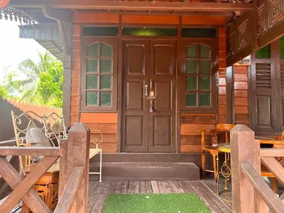 a wooden door of a house with a table and chairs at Homestay Jasmin in Taiping