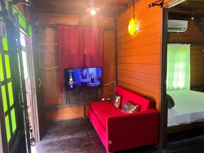 a small room with a red couch and a tv at Homestay Jasmin in Taiping