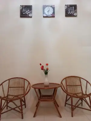 two chairs and a table with a vase with flowers at Lily Impiana Homestay in Baling