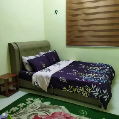 a bedroom with a bed with purple sheets and a rug at Lily Impiana Homestay in Baling
