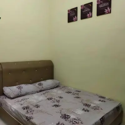 a bed in a bedroom with three pictures on the wall at Lily Impiana Homestay in Baling