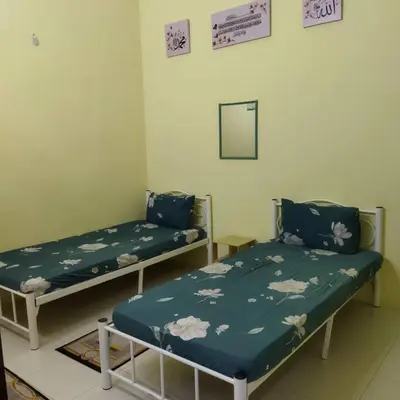 two beds in a room with a mirror at Lily Impiana Homestay in Baling