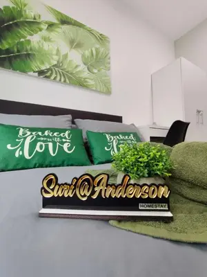 a bed with green pillows and a sign on it at Suri Homestay Anderson Ipoh in Ipoh