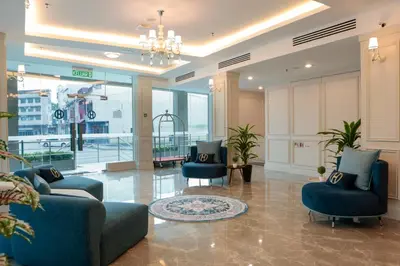 a lobby with two blue chairs and a chandelier at The Host Hotel in Ipoh