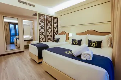 a hotel room with two beds and a mirror at The Host Hotel in Ipoh