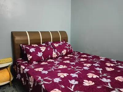 a bed with a purple comforter and two pillows at Seri Raban Homestay in Kampong Kuala Chegar