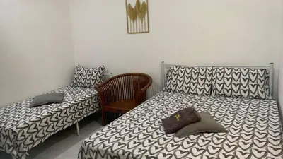 a bedroom with two beds and a chair at Bilik Umairah in Gerik