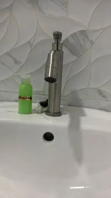a faucet and a green bottle sitting on a sink at Bilik Umairah in Gerik