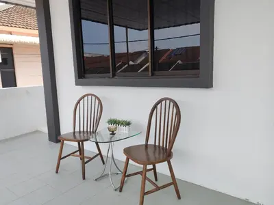 two chairs and a glass table on a patio at 23 Inn Kingbed Room with Balcony in Bukit Mertajam
