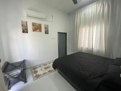 a bedroom with a black bed and a window at Maison Helysa Homestay in Lumut