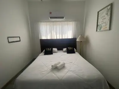 a bedroom with a large white bed with a window at Maison Helysa Homestay in Lumut