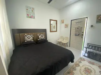 a bedroom with a black bed and two chairs at Maison Helysa Homestay in Lumut