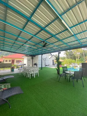 a covered patio with tables and chairs and a pool at Maison Helysa Homestay in Lumut