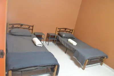 two beds in a room with a table at Yim's Homestay in Kuala Kubu Baharu