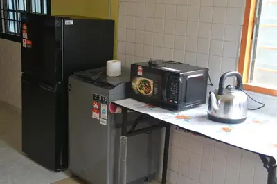 a microwave sitting on a counter next to a refrigerator at Yim's Homestay in Kuala Kubu Baharu