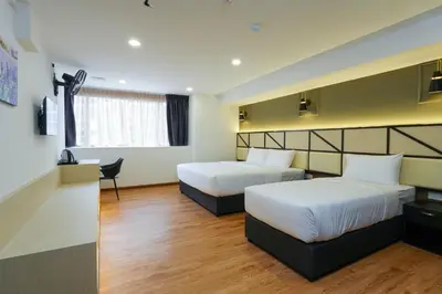a hotel room with two beds and a desk at Merits Hotel Cameron Highlands in Cameron Highlands
