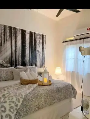 a bedroom with a bed with a painting on the wall at Cottage Near Lake Garden in Taiping