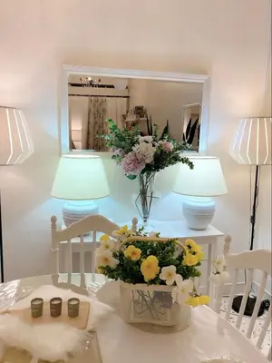 a vase of flowers on a table with two lamps at Cottage Near Lake Garden in Taiping