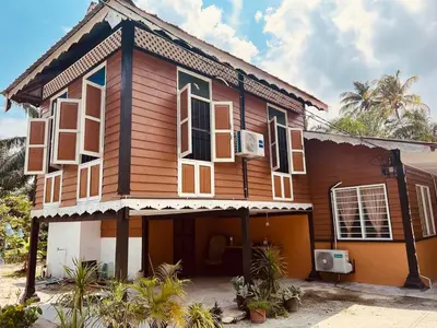 a wooden house with white windows and palm trees at Inap Desa R'Sawit Pintu A in Sekincan