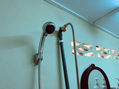 a shower with a hose hooked up to a wall at Inap Desa R'Sawit Pintu A in Sekincan