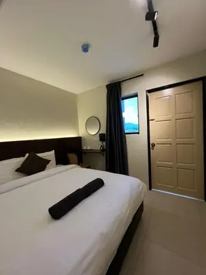 a bedroom with a white bed with a black pillow on it at Kangsar KK Hotel in Kuala Kangsar