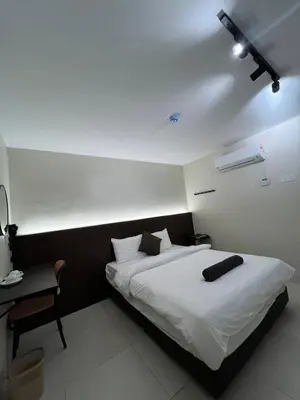 a bedroom with a large white bed and a desk at Kangsar KK Hotel in Kuala Kangsar