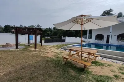 a wooden bench with an umbrella next to a pool at Grand Aeden Villa in Kuala Kangsar