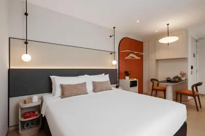 a bedroom with a large white bed and a kitchen at Citadines Tanjung Tokong Penang in George Town