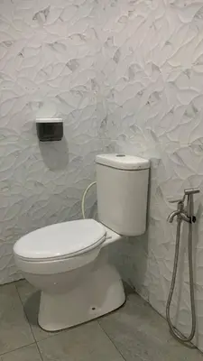 a white toilet in a bathroom with a wall at Bilik Naqiah in Gerik