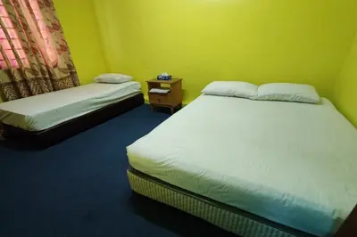 a bedroom with two beds and a night stand with a bedskirts at D'BJ Motel in Bayan Lepas