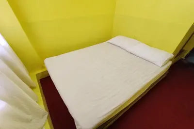 a small bed in a room with a yellow wall at D'BJ Motel in Bayan Lepas