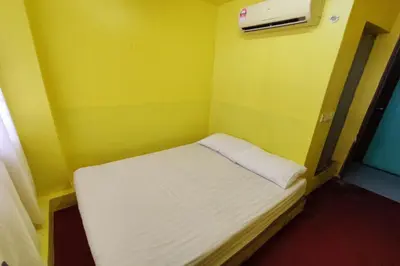 a small bed in a room with a yellow wall at D'BJ Motel in Bayan Lepas