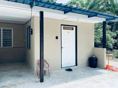 a house with a white door and a pink chair at Inap Desa R'Sawit Pintu B in Sekincan