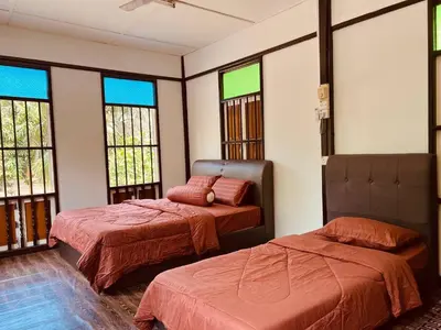 two beds in a room with windows at Inap Desa R'Sawit - A dan B in Sekincan