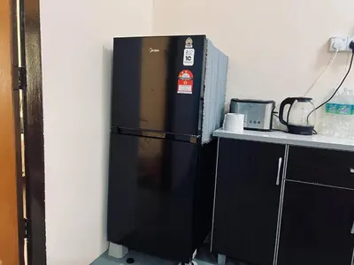 a black refrigerator in a kitchen next to a counter at Inap Desa R'Sawit - A dan B in Sekincan