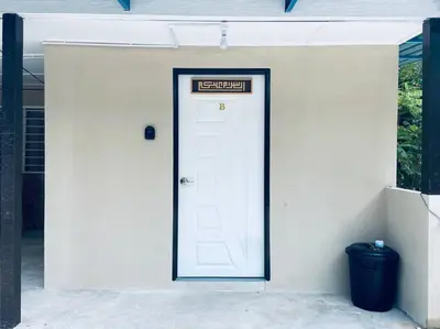 a white door with a sign on it next to a trash can at Inap Desa R'Sawit - A dan B in Sekincan