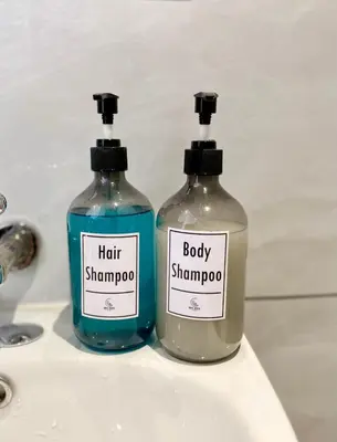 two bottles of soap sitting on a bathroom sink at The 6N by Sky Hive in George Town