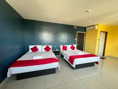 a bedroom with two beds with red and white sheets at Hotel Pinji Ipoh in Ipoh