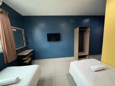 a room with two beds and a blue wall at Hotel Pinji Ipoh in Ipoh