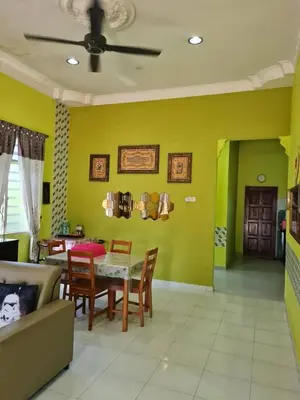 a living room with a table and chairs and yellow walls at de'berah homestay penaga in Penaga