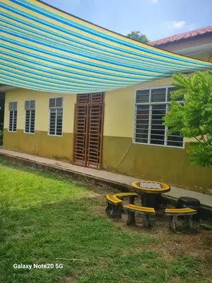 a building with a table and benches in a yard at de'berah homestay penaga in Penaga