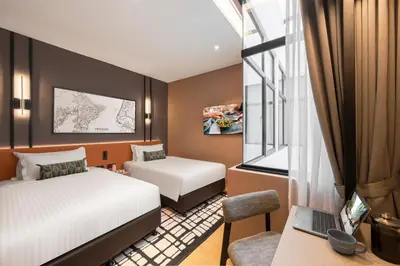 a bedroom with two beds and a desk with a laptop at Citadines Connect Cecil Georgetown Penang in George Town