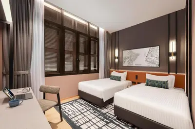 a hotel room with two beds and a desk at Citadines Connect Cecil Georgetown Penang in George Town