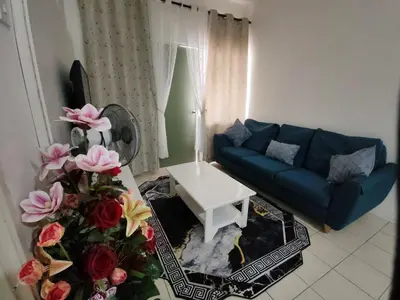 a living room with a blue couch and pink flowers at Ian's Homestay Tanah Rata C Highlands in Tanah Rata
