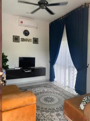 a living room with blue curtains and a tv at HOMeSTAY DAMIA - Islam Homestay Only in Teluk Intan