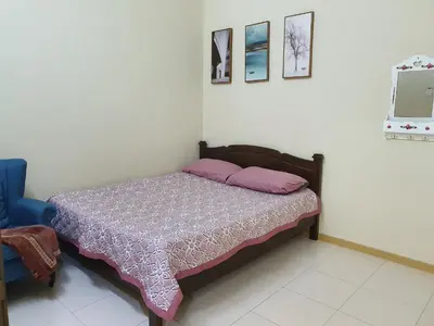 a bedroom with a bed and a blue chair at Teratak Ayuni with Private pool in Batu Gajah