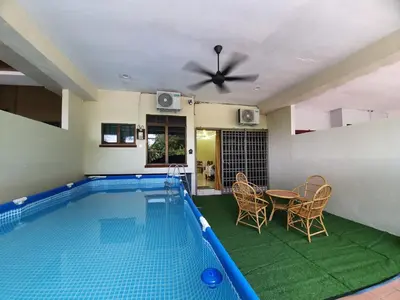 a swimming pool in a house with a table and chairs at Teratak Ayuni with Private pool in Batu Gajah