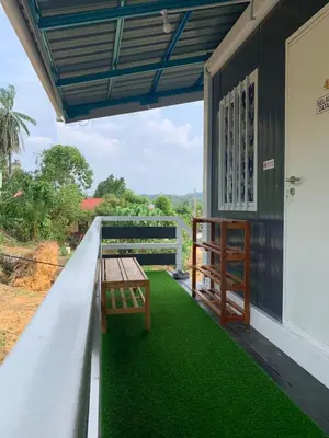 a porch with green grass and a table on it at Farhani Cabin Stay in Kampong Batu Lima