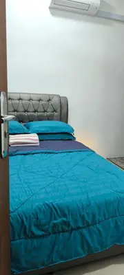 a bed with a blue comforter and blue pillows at AMI Homestay & Guest House in Gua Musang
